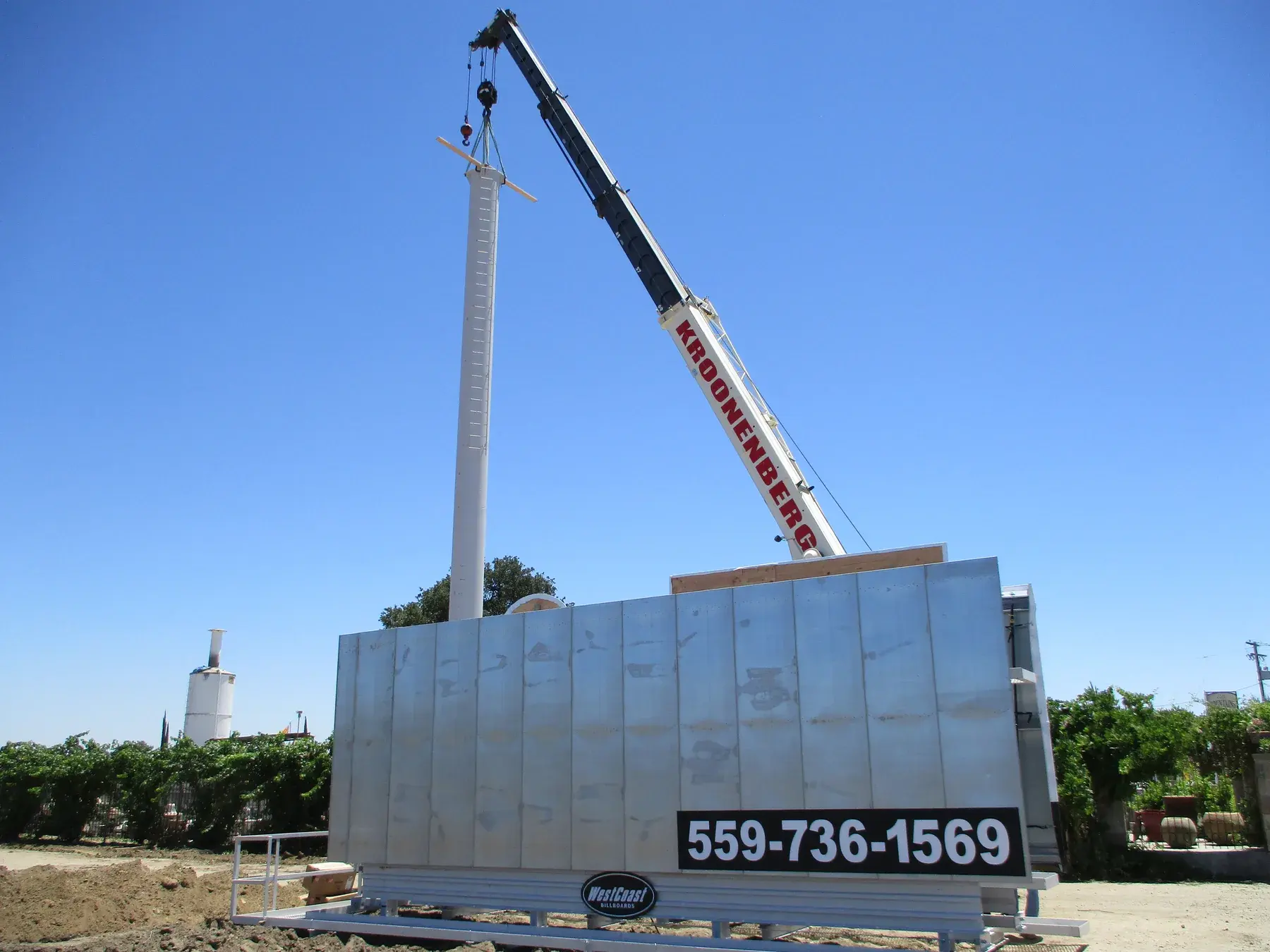 Crane lifting a billboard support pole into place