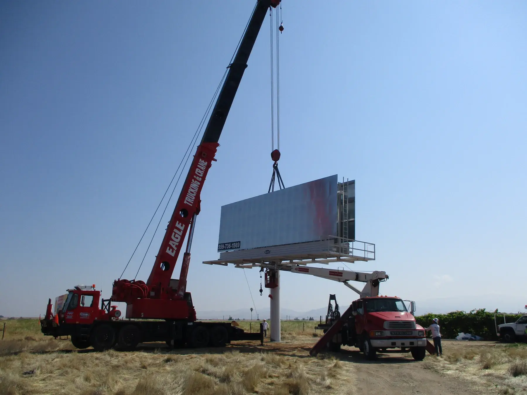 Two cranes working together during a billboard installation